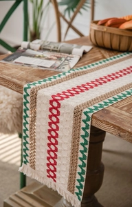 Detail of cotton linen table runner with woven tassels and red-green stripes