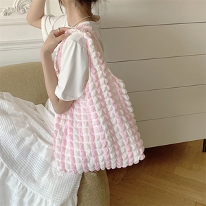 Shoulder bag with pink and white bubble texture fabric shown on model in home setting