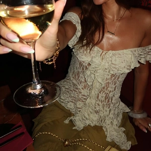 Detail of off-white lace off-shoulder top with ruffle trim and elegant lace textures
