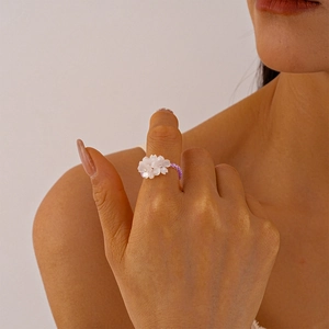 Close-up of beaded flower ring with purple beads and white resin petals on finger
