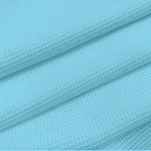 Macro shot of light blue waffle knit fabric showing texture and layering on men polo shirt
