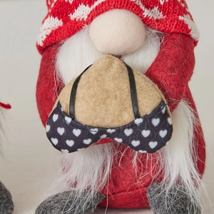 Chritmas knit gnome with red hat and white beard holding a heart shaped charm