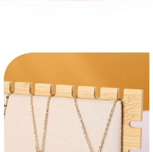 Close-up of bamboo necklace display rack with beige velvet backboard and U-shaped hooks