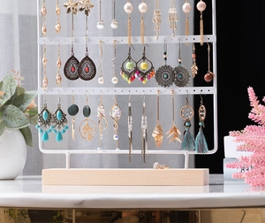 Detail view of white metal jewelry organizer with wooden base and multiple earring holes