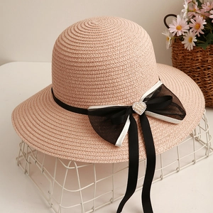 Cappello di paglia rosa con fiocco nero e spilla di perle a cuore su espositore