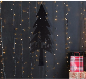 Macro shot of black Christmas tree silhouette decoration with deer cutouts and LED lights