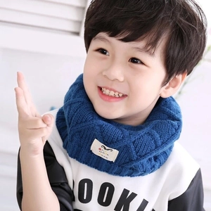 Detail of dark blue knitted kids neck warmer featuring a small decorative label