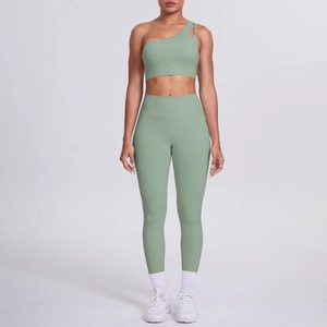 Close-up of sage green two-piece yoga set with one-shoulder sports bra and high-waist pants