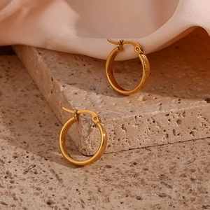 Detail of 20mm gold-plated stainless steel earrings with oblique stripes on stone surface
