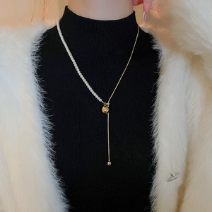 Detail of elegant gold ball slider clasp and pearl tassel on Y-shaped necklace