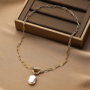 Detailed shot of baroque pearl pendant with gold paperclip chain and OT clasp on a velvet box