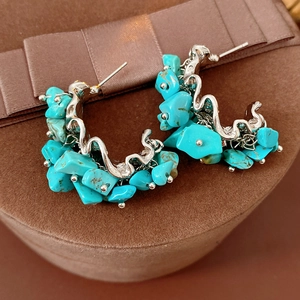 Gros plan de boucles d'oreilles C en argent avec pierres turquoise sur velours brun