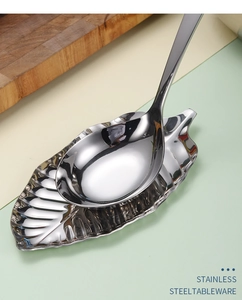 Macro detail of leaf-shaped stainless steel spoon rest with fine texture and golden spoon