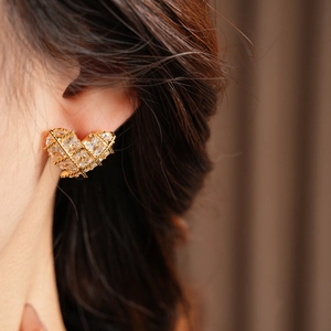 Vue macro de boucles d'oreilles cœur plaqué or 18k avec zircone cubique sur une oreille