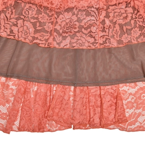 Détail de la dentelle florale corail et des coutures en maille marron sur la robe