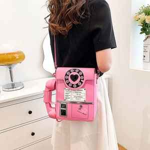 Pink retro telephone shoulder bag worn by model in a stylish home interior setting