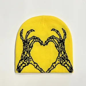 Close-up of a bright yellow knitted beanie featuring black skull hands heart pattern