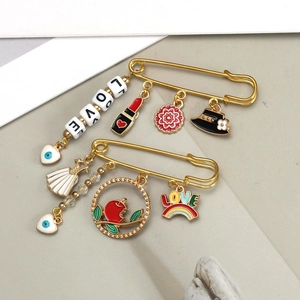 Detailed close-up of golden metal safety pins featuring colorful enamel love and eye charms