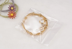 Detailed shot of an 18K gold-plated adjustable wire bracelet with cross and crystal charms