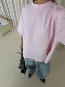 Close-up of pink cotton T-shirt featuring delicate white lace trim on sleeves and hem