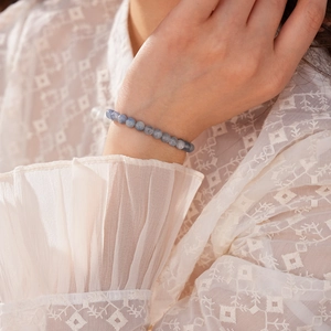 Detail of blue kyanite beaded bracelet on wrist with elegant white lace embroidery