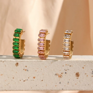Detailed close-up of C-shaped 18K gold plated earrings set with green, pink, and white cubic zirconia