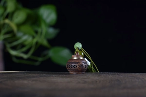 Detailed view of hollow wooden sachet pendant with Fu character engraving and green beads