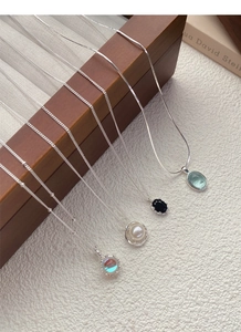 Detail view of S925 sterling silver necklaces with pearl and gemstone pendants on wood