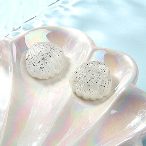 Macro shot of glittery white resin shell accessories on an iridescent shell tray