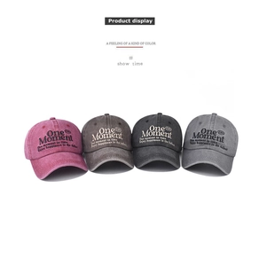 Detail view of four washed cotton baseball caps with One Moment embroidery in various colors