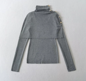 Detail of grey turtleneck knitwear with shawl overlay and four gold decorative buttons