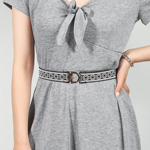Detail of a black elastic belt with white geometric patterns and a gold interlocking buckle