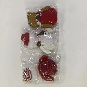 Vue détaillée de trois ornements de Noël en peluche assortis dans leur emballage d'origine