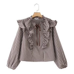 Detail of ruffle neckline and tie string on brown gingham plaid long sleeve blouse
