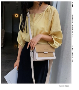 Detail of a chic two-tone crossbody bag with wide woven strap and metal flap closure