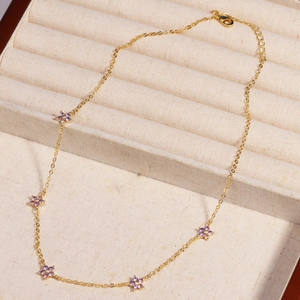 Close-up of gold chain necklace with five purple gemstone flower pendants in jewelry box