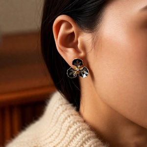 Gros plan détaillé des boucles d'oreilles fleurs vintage en émail noir doré avec diamant