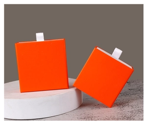 Detail of square orange drawer jewelry boxes with white pull ribbons on stone texture