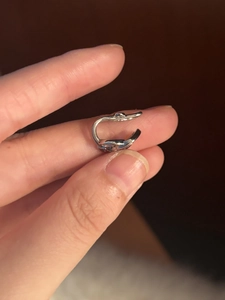 Detailaufnahme einer silbernen Ohrklemme in Nagelform mit Zirkonia-Akzenten in der Hand