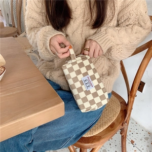 Gros plan d'une trousse à maquillage en velours côtelé à carreaux avec étiquette Wild Flower