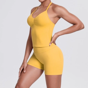 Detail of yellow high-waisted yoga shorts and V-neck sports bra on a female model
