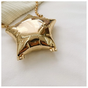 Detail of star-shaped golden mini bag with reflective mirror finish and bead chain