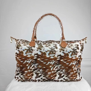 Detail of weekender bag featuring brown animal print canvas and leather handles