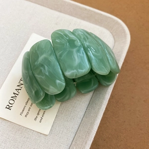 Close-up of light green acrylic bracelet with marble pattern and resin texture