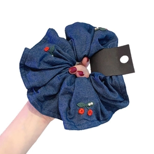 Navy blue denim scrunchie with red cherry embroidery and white pearls on white background