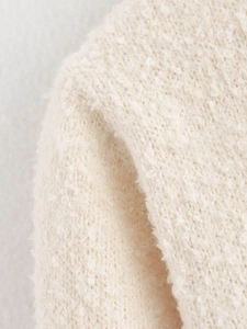 Macro shot of off-white boucle knit fabric texture showing soft textured details