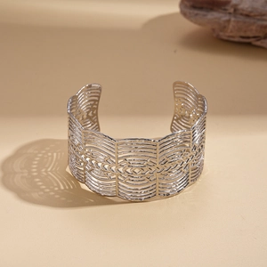 Detailed view of silver open cuff bracelet with woven texture on sandy background