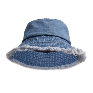 Detailed macro view of denim bucket hat featuring frayed raw edges and classic blue texture