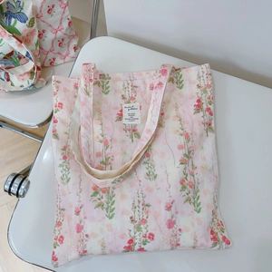 Detailed macro view of pink floral canvas tote with white text patch and natural texture