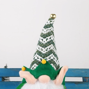 Close-up of a Christmas gnome with a green knit hat, golden bell, and long white beard